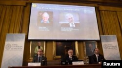Tomas Sjostrom, anggota Komite Nobel untuk Ilmu Ekonomi, Goran K. Hansson (Sekjen Royal Swedish Academy of Sciences) dan Per Stromberg, Ketua Komite Nobel untuk Ilmu Ekonomi mengumumkan pemenang tahun 2016, dan menayangkan profil Oliver Hart dan Bengt Holmstrom di layar lebar, di Stockholm, Swedia, 10 Oktober 2016. (TT News Agency/Stina Stjernkvist/ via REUTERS)