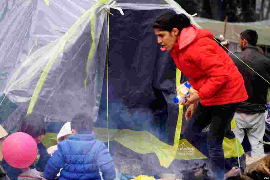 A Syrian mother dashes to stop her kids from playing too close to an open wood fire. (Jamie Dettmer for VOA)