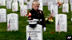 Christian Jacobs, 5, of Hertford, North Carolina, dressed as a Marine, pauses at his father's gravestone on Memorial Day at Arlington National Cemetery in Arlington, Virginia. on May 30, 2016. 