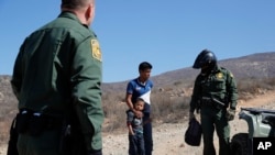 A Guatemalan father and son, who crossed the U.S.-Mexico border illegally, are apprehended by U.S. Border Patrol agents, June 28, 2018, in San Diego, California.. 