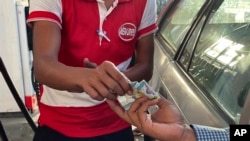 FILE - A driver hands over Myanmar kyats to an attendant as payment for fuel at a gas station in Botahtaung township in Yangon, Myanmar on Nov. 12, 2021.