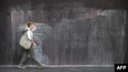 A woman walks past graffiti on an immigration detention hotel in Melbourne on March 24, 2022.