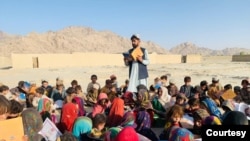 Afg'onistonlik ta'lim huquqlari faoli Matiulloh Vesa ochiq maydonda bolalarga dars o'tmoqda.
