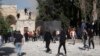 Palestinians work to extinguish a tree that caught fire as Israeli police clashed with protesters at the Al Aqsa Mosque compound, in Jerusalem's Old City, April 22, 2022.