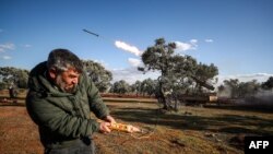 A Syrian rebel fighter remotely-fires a rocket from a truck-mounted launcher at a position in the countryside of Idlib towards regime forces positions in the southern countryside of Syria's Aleppo province on Feb. 10, 2020.