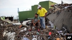 A neighbor comforts Roberto Ganchoso is as he sits in what's left of his neighborhood, watching a bulldozer demolish a hotel next door in Pedernales, Ecuador, April 23, 2016. President Rafael Correa has said last week's earthquake caused $3 billion in damage.