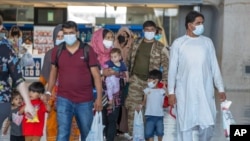 Families evacuated from Kabul, Afghanistan, walk through the terminal to board a bus after they arrived at Washington Dulles International Airport, in Chantilly, Va., Aug. 28, 2021.