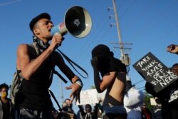 Protesters block a street outside the police station June 10, 2020, in Florissant, Mo. Several hundred protesters were calling attention to a video that appears to show a Florissant police detective hitting a man with his police car.
