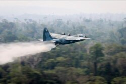 In a photo released by Brazil's Ministry of Defense, a C-130 Hercules aircraft dumps water to fight fires burning in the Amazon rainforest, in Brazil, Aug, 24, 2019.