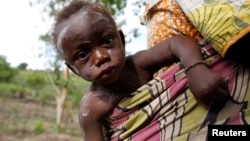 A child from Bunia in eastern Democratic Republic of Congo suffering from chickenpox is carried by her mother at the Kyangwali refugee settlement in Hoima district in Western Uganda, March 25, 2014. (REUTERS/Thomas Mukoya)