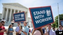 People gather at the Supreme Court awaiting a decision in an Illinois union dues case, Janus vs. AFSCME, in Washington, June 25, 2018. The Supreme Court says government workers can't be forced to contribute to labor unions that represent them in collective bargaining, dealing a serious financial blow to organized labor.
