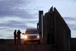 FILE - In this Nov. 21, 2018 file photo, United States Border Patrol agents stand by a vehicle near one of the border walls separating Tijuana, Mexico and San Diego, in San Diego.