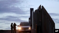 FILE - In this Nov. 21, 2018 file photo, United States Border Patrol agents stand by a vehicle near one of the border walls separating Tijuana, Mexico and San Diego, in San Diego.