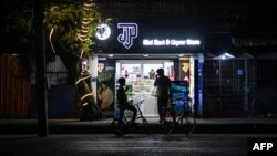 ရန်ကုန်မြို့ပေါ် မီးပျက်နေစဉ် စတိုးဆိုင်တခုရှေ့ စကားပြောနေကြတဲ့ လူတချို့ (ဇန်နဝါရီ ၁၄၊ ၂၀၂၅)