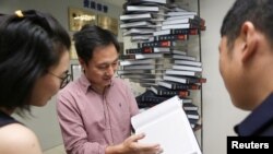 Ilmuwan He Jiankui menunjukkan buku "The Human Genome", yang dia edit di perushaannya Direct Genomics di Shenzhen, Provinsi Guangdong, China, 4 Agustus 2016. 