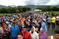 FILE - People cross the Colombian-Venezuelan border over the Simon Bolivar international bridge in Cucuta, June 10, 2019.