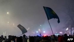 Para pendemo mengibarkan bendera dalam aksi unjuk rasa di Almaty, Kazakhstan, pada 4 Januari 2022. (Foto: AFP/Abduaziz Madyarov)