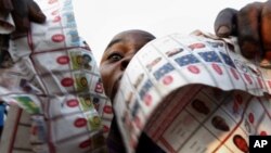 Supporters of oppositions candidate Etienne Tshisekedi parade what they claim are badly printed fraudulent photocopies of election ballots they say they found in the Bandal commune in Kinshasa, Democratic Republic of Congo, Monday Nov. 28, 2011.