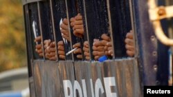 FILE - Student protesters are seen gripping the bars of a prison vehicle as they are transported to a court in Letpadan, March 11, 2015. Myanmar's opposition National League for Democracy (NLD) demanded an inquiry into clashes between police and protesters. 