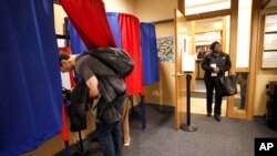 FILE - A voter waits her turn, Feb. 24, 2020, as others vote at the Cambridge City Hall annex, on the first morning of early voting in Massachusetts.