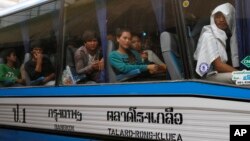 FILE - Cambodian migrant workers sit in a bus upon arrival at Cambodia-Thailand's international border gate in Poipet, Cambodia, from Thailand, Tuesday, June 17, 2014.