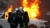 Firefighters try to extinguish flames from a burning car during a demonstration of the yellow vest movement in Nantes, France, Jan. 12, 2019.