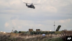 FILE - A Russian helicopter flies above Hemeimeem air base in Syria, Jan. 20, 2016. А Russian military official dismissed as "propaganda" claims by the Islamic State group that it successfully attacked Russian military hardware at an air base near Palmyra.