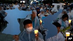 Warga Korea Selatan di Seoul (9/6), melakukan aksi unjuk rasa dengan membawa peta Semenanjung Korea dan menyalakan lilin, berharap bisa terwujudnya perdamaian di Korea dalam KTT Trump-Kim di Singapura.