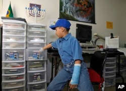 Moshe Kai Cavalin, 10, keeps his college classes assignments organized in separate clear plastic drawers at his home studio in Downey, Calif.