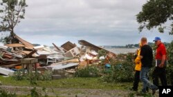 FILE - Members of a local Baptist Men's Association walk past a home that was destroyed after the remnants of tropical storm Beryl spun off a tornado that destroyed homes and damages dozens of others in the Pelletier community near Swansboro, NC on Wednesday, May 30, 2012.