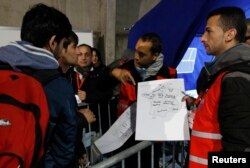 Migrants look at a map of France at a processing center to be registered on the second day of their evacuation and transfer to reception centers in France, during the dismantlement of the camp called "the jungle" in Calais, France, Oct. 25, 2016.