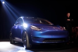 Tesla CEO Elon Musk, right, stands next to the Model Y at Tesla's design studio Thursday, March 14, 2019, in Hawthorne, Calif.