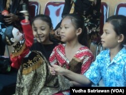 Tiga siswa SD sedang bermain menggunakan wayang golek di SD Negeri 26 Solo dalam kegiatan Wayang Masuk Sekolah, Rabu (18/7).