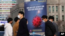 រូបឯកសារ៖ មនុស្សម្នា ដើរកាត់​ផ្ទាំងបដា​ដែល​ផ្សព្វផ្សាយ​អំពី​យុទ្ធនាការ​ឲ្យ​រក្សា​គម្លាត​ពីគ្នា​ក្នុង​សង្គម ក្នុងពេល​មាន​ការរាតត្បាត​ដោយ​ជំងឺ​កូវីដ១៩ នៅក្នុង​ទីក្រុង​សេអ៊ូល​នៃ​ប្រទេស​កូរ៉េខាងត្បូង កាលពី​ទី២៥ ខែវិច្ឆិកា ឆ្នាំ២០២០។