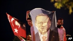 មនុស្សម្នា​កាន់​បដា​ដែល​មាន​រូប​របស់​លោក​ប្រធានាធិបតី​តួកគី Recep Tayyip Erdogan សាទរ​នៅ​ខាង​ក្រៅ​គណបក្ស​យុត្តិធម៌ និង​អភិវឌ្ឍន៍​ នៅ​ក្នុង​ក្រុង​អ៊ីស្តង់ប៊ុល កាលពី​ថ្ងៃទី២៤ ខែមិថុនា ឆ្នាំ២០១៨។