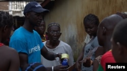 FILE - A UNICEF worker shares information on Ebola and how to help prevent its spread in Conakry, Guinea in this UNICEF handout photo.