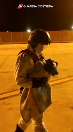 An Italian coast guard member holds a child who was evacuated from the Spanish ship Open Arms after being rescued from the Mediterranean Sea, Nov. 12, 2020, in Malta.