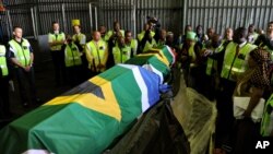 Les autorités gouvernementales, les médias et les proches entourent les cercueils, drapés dans les drapeaux sud-africains, des restes du couple Khoisan Klaas et Trooi Pienaar retournés d'Autriche, à l'aéroport international Or Tambo à Johannesburg, 20 avr