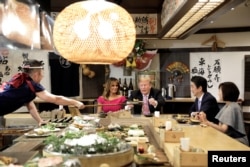 U.S. President Donald Trump, with first lady Melania Trump, receives a plate of food from a chef as they and Japanese Prime Minister Shinzo Abe and his wife Akie Abe have a couples dinner in Tokyo, May 26, 2019.