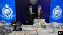 Senior Superintendent Li Kwai-wah, left, of Hong Kong Police, and senior bomb disposal officer Alick McWhirter pose with the seized evidence during a news conference at police headquarters in Hong Kong, July 6, 2021.(AP Photo/Kin Cheung)