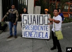 FILE - Anti-government protesters show a sign reading in Spanish "Guaido, President of Venezuela" after a rally demanding the resignation of President Nicolas Maduro in Caracas, Jan. 23, 2019.