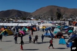 FILE - Migrants walk inside a former concert venue serving as a shelter in Tijuana, Mexico, Dec. 3, 2018.