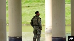 A member of the Texas National Guard looks across the Rio Grande to Mexico from the U.S. at Eagle Pass, Texas, Aug. 26, 2022.