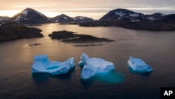 FILE - Large icebergs float away as the sun rises near Kulusuk, Greenland, Aug. 16, 2019. 