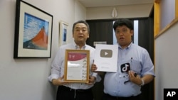 Daikyo Security Chief Executive Daisuke Sakurai, right, and General Manager Tomohiko Kojima hold the awards they have won recently for their Tik Tok videos Aug. 22, 2022. (AP Photo/Yuri Kageyama)