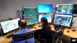 FILE - Hurricane specialists track developments at the National Hurricane Center in Miami, June 1, 2022.