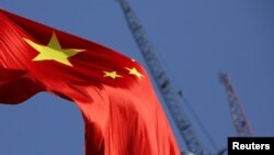 China's national flag is seen in front of cranes on a construction site at a commercial district in Beijing, China, Jan. 26, 2016. 