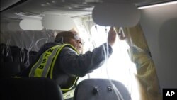 FILE - NTSB Investigator-in-Charge John Lovell examines the fuselage plug area of an Alaska Airlines flight after an emergency landing in Portland, Oregon, Jan. 7, 2024. (National Transportation Safety Board via AP)
