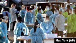In this June 27, 2020, file photo, medical personnel prepare to test hundreds of people lined up in vehicles in Phoenix's western neighborhood of Maryvalefor free COVID-19 tests organized by Equality Health Foundation, which focuses on care in underserved communities. (AP Photo)