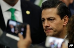 Invited guests take cell phone pictures of Mexico's President Enrique Pena Nieto following his address in response to the U.S. presidential election in Mexico City, Wednesday, Nov. 9, 2016.